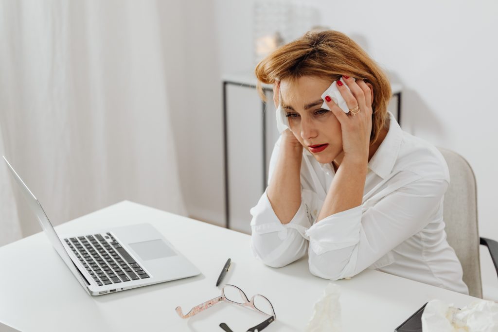A woman crying and stressed at her desk